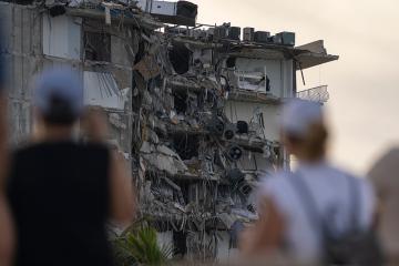 People watch a partially collapsed building 
